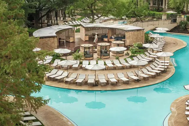 Ritz-Carlton Las Colinas in Irving, pool with lounge chairs, umbrellas and greenery